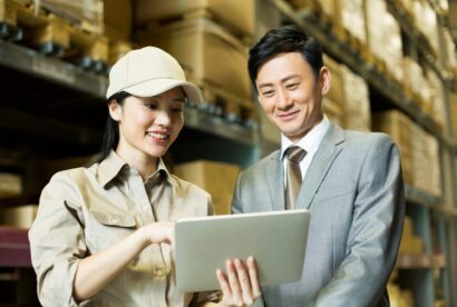Female logistics staff showing digital tablet to businessman