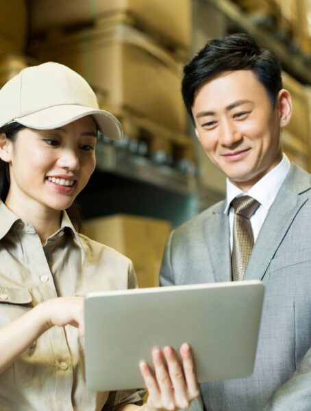 Female logistics staff showing digital tablet to businessman