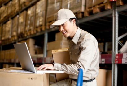 Male Chinese warehouse worker using a laptop