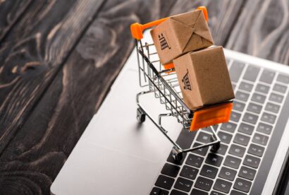toy boxes in small shopping cart on laptop, e-commerce concept